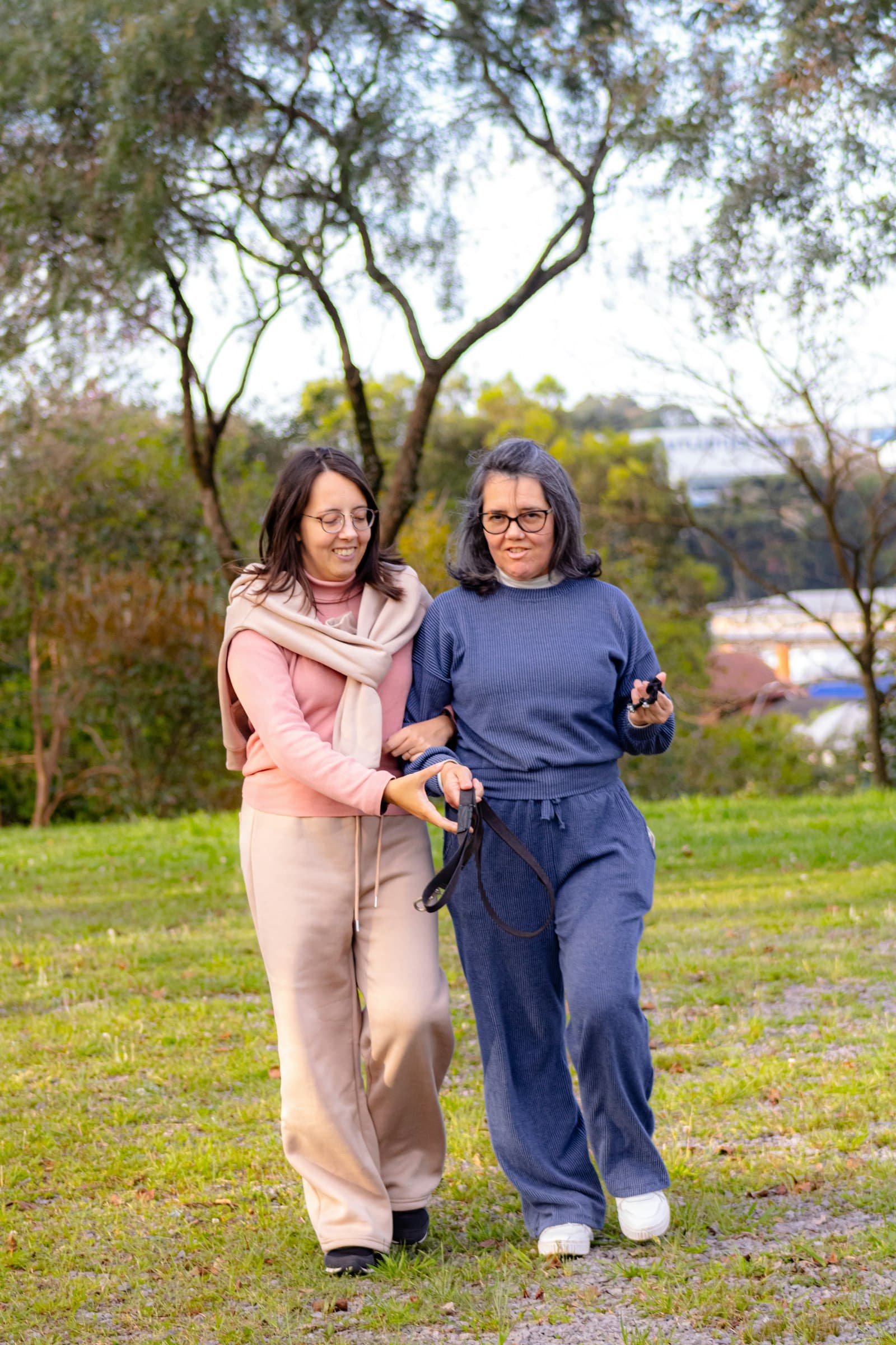 A staff member walks alongside an adult participant in a park, supporting community engagement